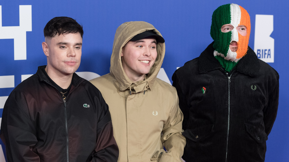 Kneecap members Moglai Bap in a black bomber jacket, Mo Chara in a beige hooded jacket and black baseball hat and DJ Provai in a black bomber jacket and green white and orange Irish tricolor balaclava attend the British Independent Film Awards 