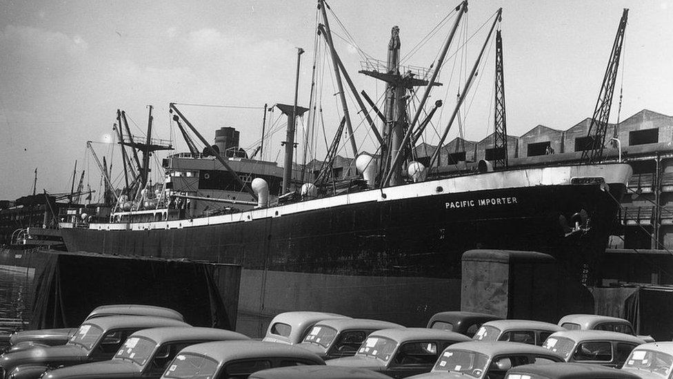 1948: SS Pacific Importer in the Manchester Ship Canal. Cars waiting for transport line the quay.