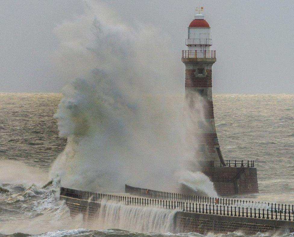 A wave appears on the edge of a wave breaking over a seawall