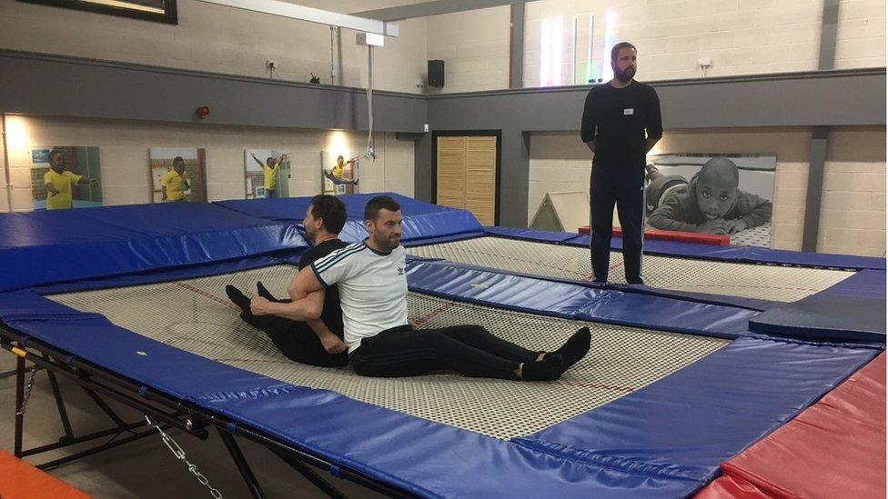 Two men sitting on the trampoline back-to-back