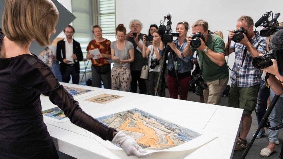 An official displays artwork during a press preview of the first masterpieces of the estate of Cornelius Gurlitt at the Museum of Fine Arts Bern (07 July 2017)