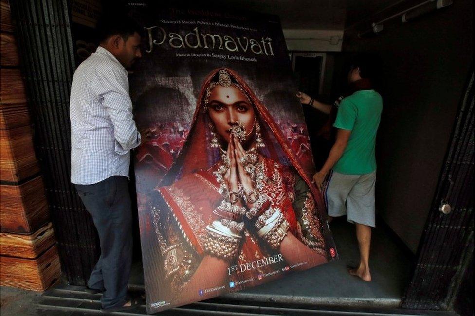 Workers carry a poster advertising upcoming Bollywood film "Padmavati" towards a ticket selling counter in a cinema hall in Kolkata, India, November 28, 2017.