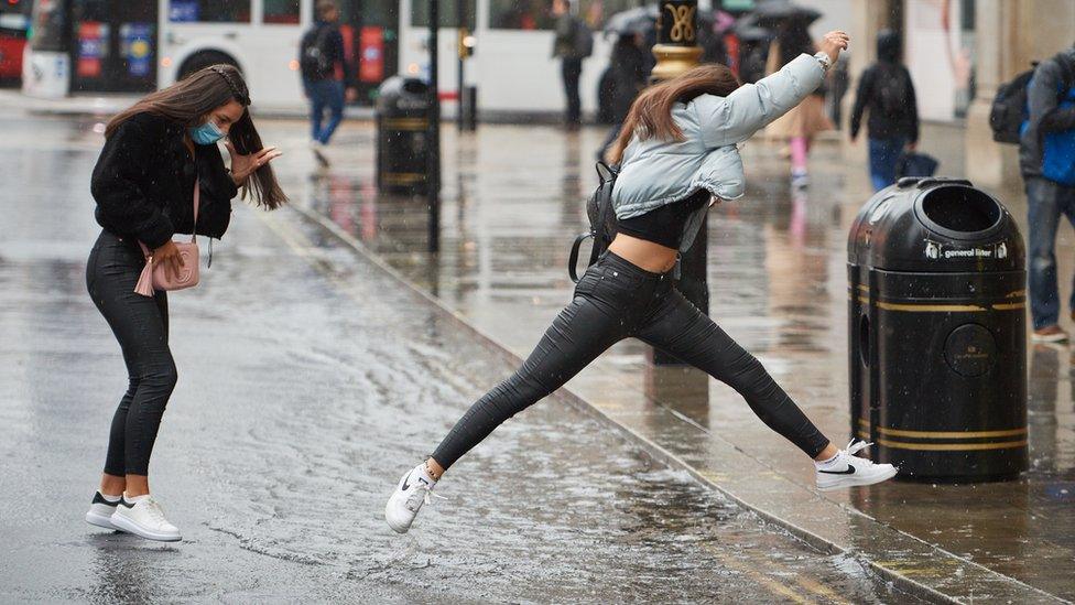 Woman jumps over puddle