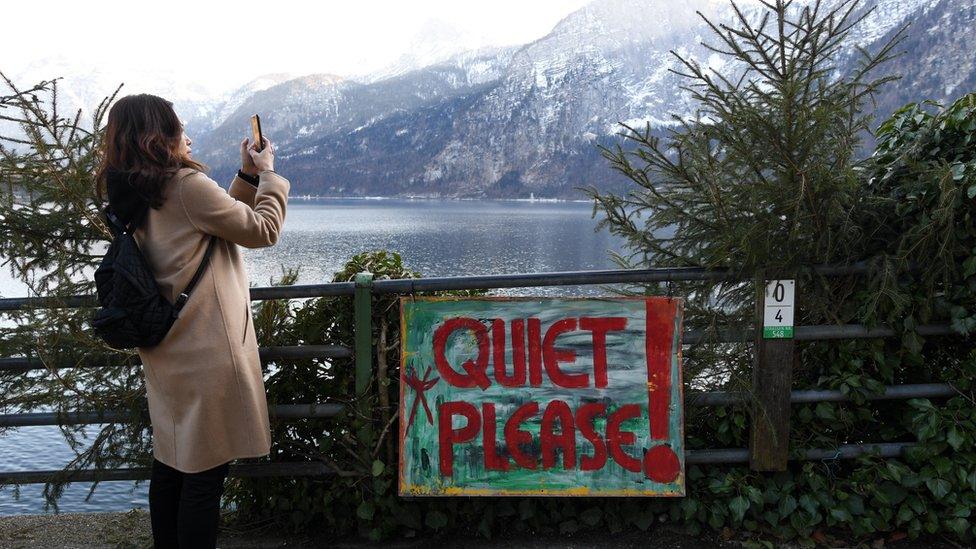 A tourist takes photos in the town center in Hallstatt