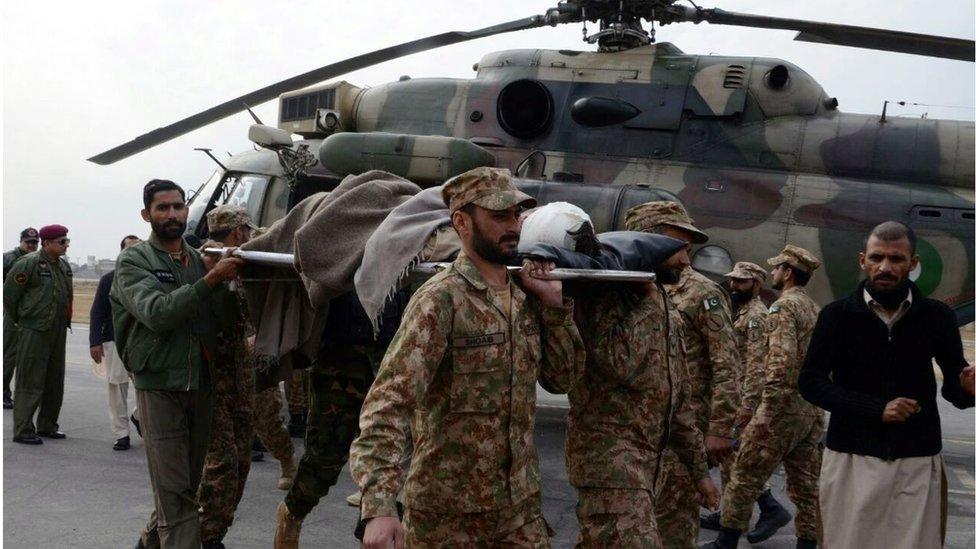 Pakistani soldiers walking with a stretcher in front of a helicopter carry an injured victim of a bomb blast in Parachinar, Peshawar, Pakistan, on 21 January 2017.