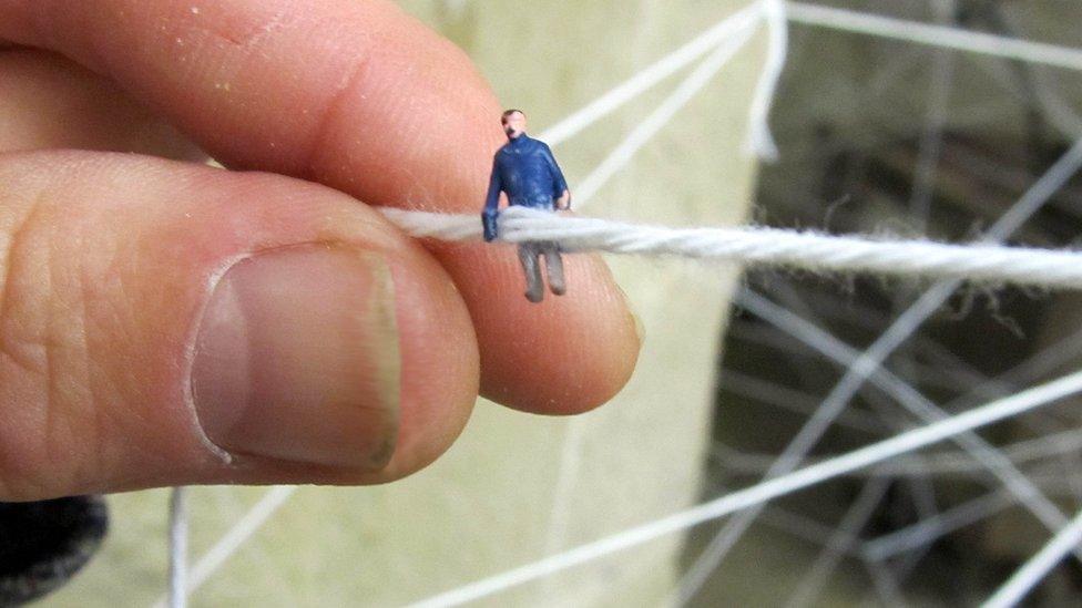 Tiny figures in a web of fabric