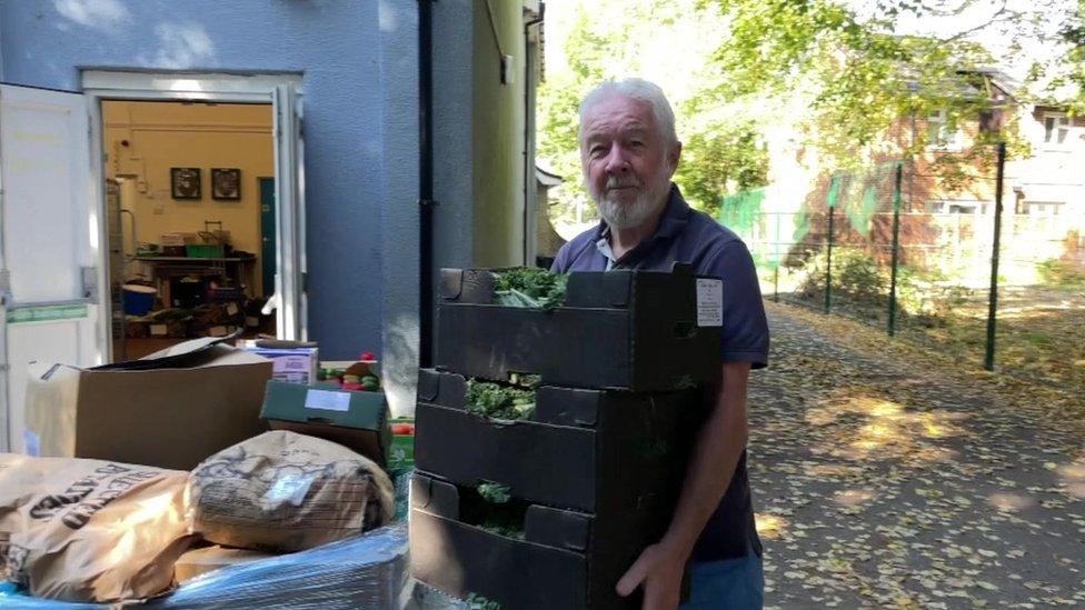 man carrying crates of vegetables