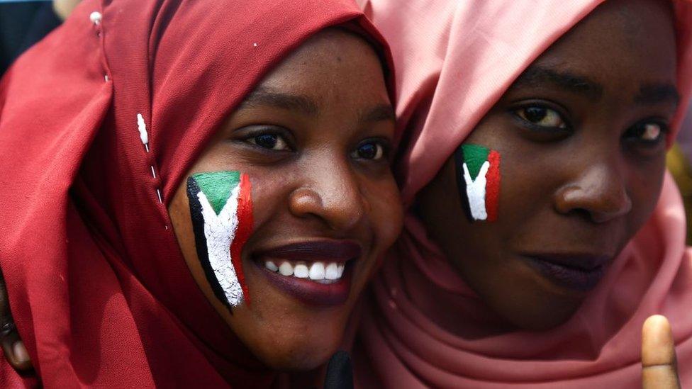 Sudanese women with national flags painted on their faces take part in a rally.