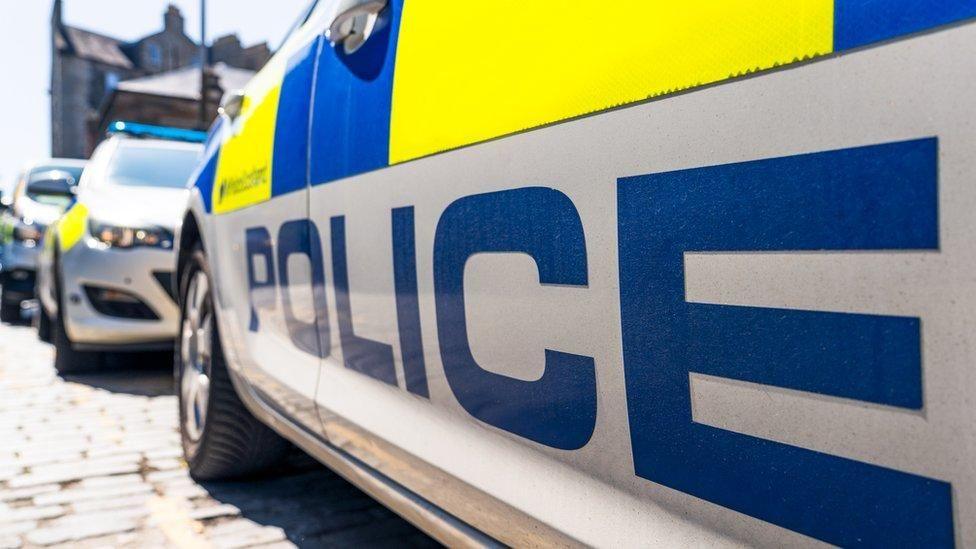 Marked Police Scotland cars parked on a cobbled street