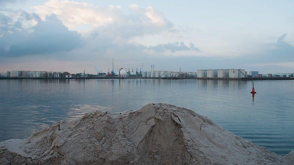 Potash pile in front of water and industrial landscape