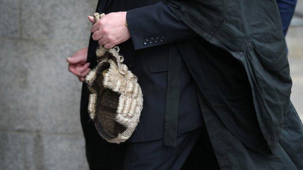 A barrister holds his wig as he arrives at The Old Bailey on 27 July 2015