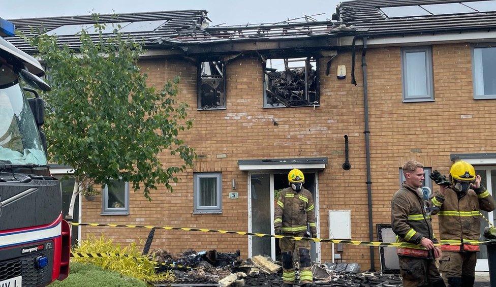 Firefighters outside the damaged house