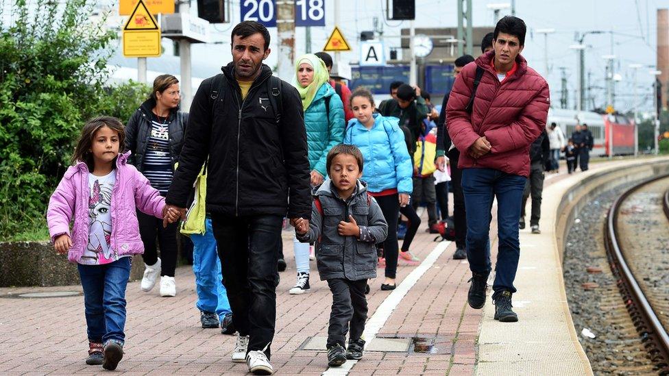 Migrants walk to get a bus after their arrival at the train station in Dortmund, western Germany, on September 6, 2015.