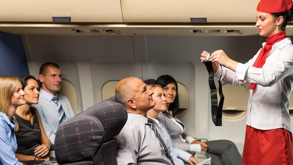 A flight attendant doing a safety demonstration