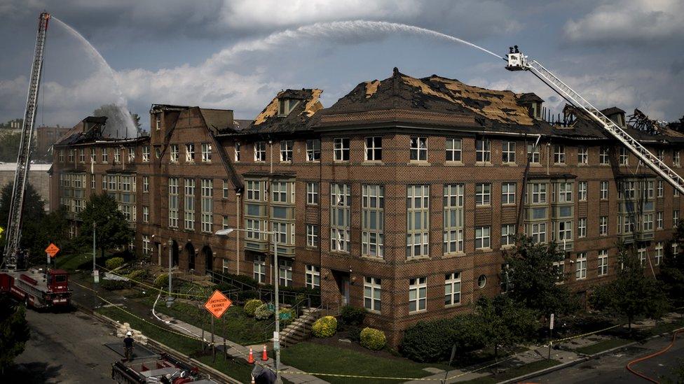 Fire trucks from the U.S. Navy and DC Fire Department spray water into the Arthur Capper Senior Apartments in Southeast Washington the day after a fire destroyed the building