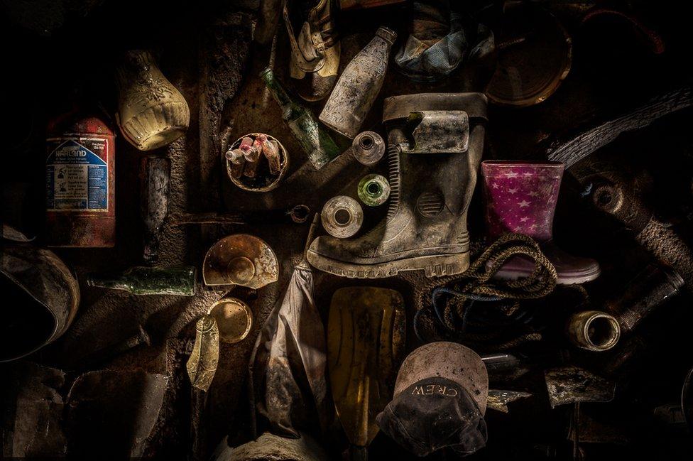 An arrangement of old Wellington boots crockery, caps and a fire extinguisher from the bottom of Lake Windermere