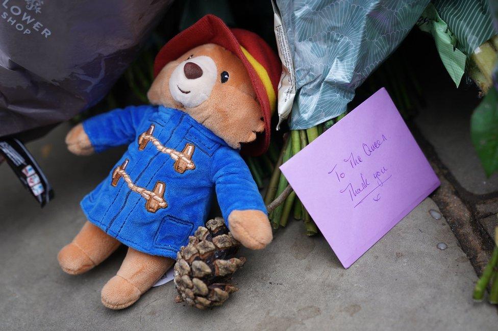 A Paddington bear soft toy and a card lay outside Buckingham Palace