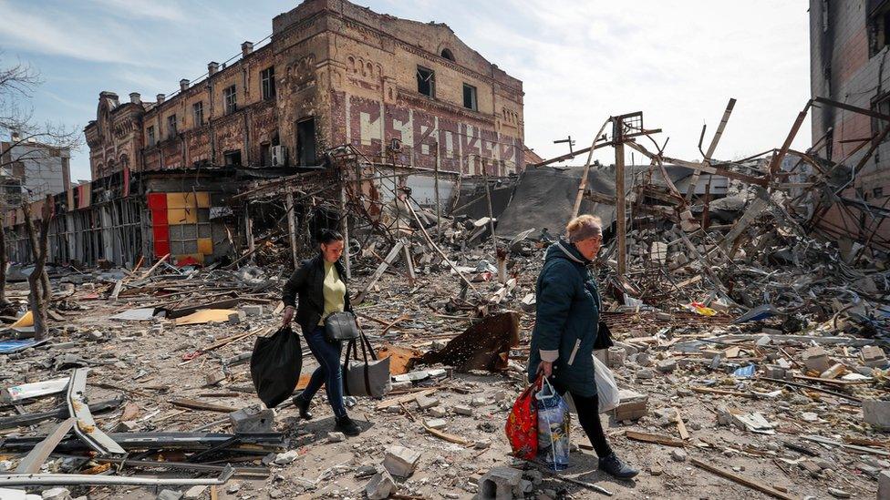 Residents carry their belongings near buildings destroyed in the course of the Ukraine-Russia conflict, in Mariupol