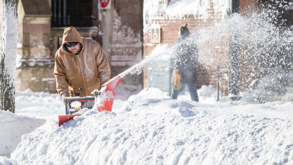 A man clears snow away from his home in Boston