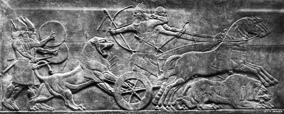 Circa 700 BC, Assyrians in a chariot, armed with bows and arrows, taking part in a lion hunt, on a frieze.