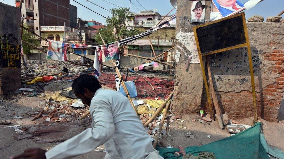 A man walks past a building destroyed during clashes over the new citizenship law, at Mustafabad, on February 26, 2020 in New Delhi