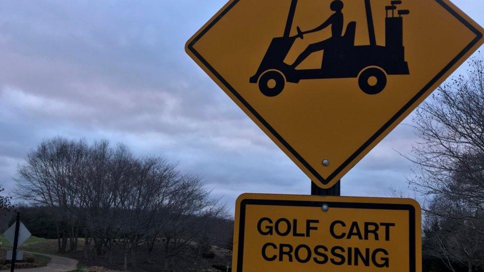 A road sign that marks a place for golf carts to cross