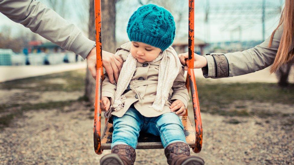 Child on a swing in between her parents