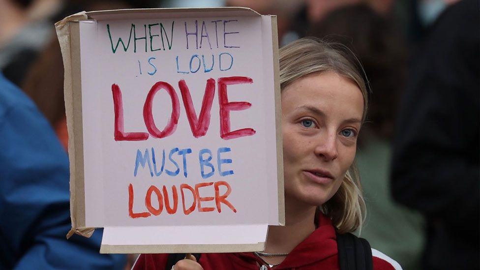 An anti-racist protester holds a sign as they gather in Brentford, west London