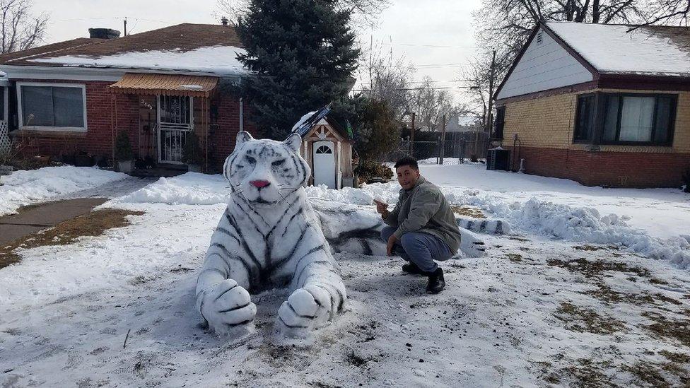 A member of the Mosley family kneels next to the tiger sculpture