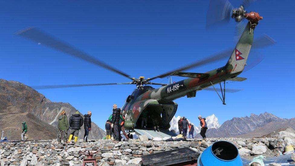 A helicopter transports construction materials to the site