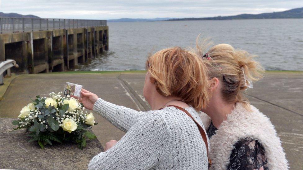 People look at a floral tribute left at Buncrana pier