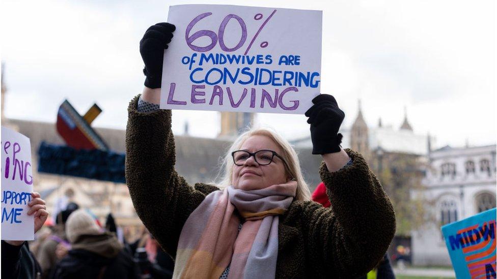 A protestor holds a placard that reads "60% of midwives are considering leaving" during a protest on a maternity "crisis" in London