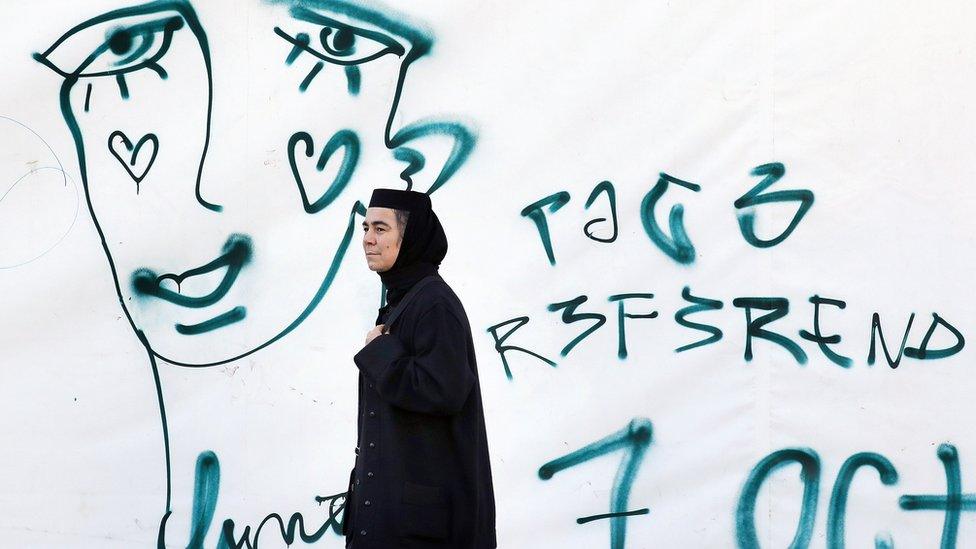 A Romanian Orthodox nun passes by a graffiti symbolizing the crying face of a LGBT community member on 5 Oct