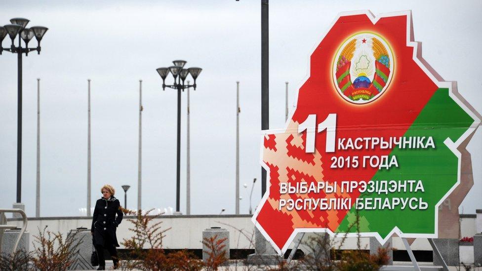 A woman walks past the Belarussian presidential election banner