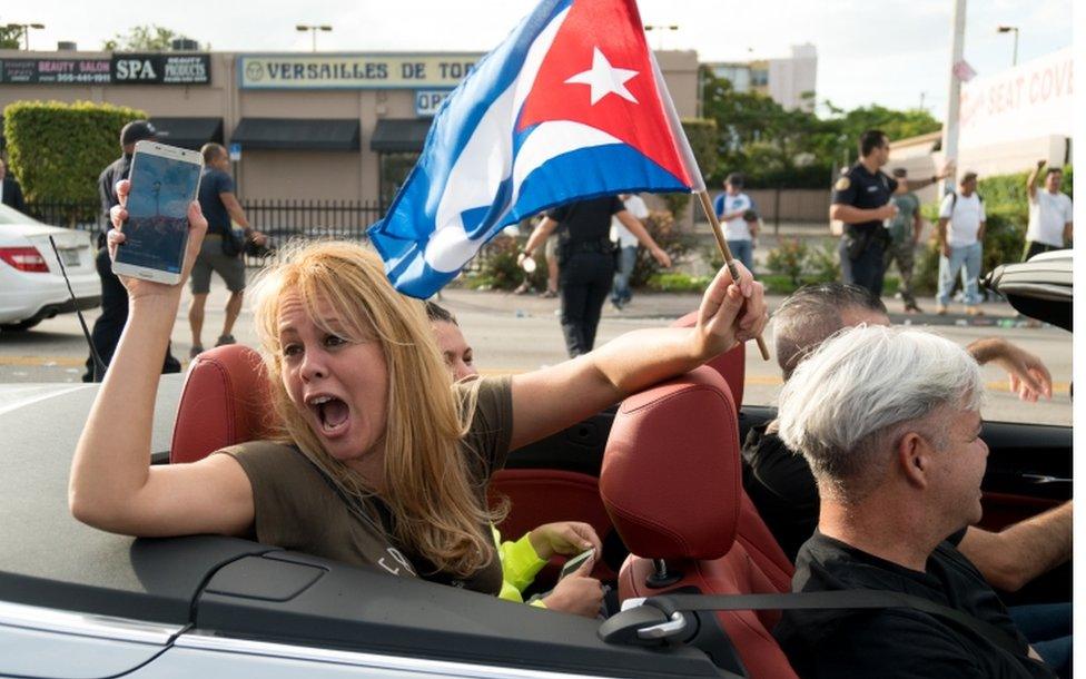 People react to news of the death of former Cuban President Fidel Castro outside the restaurant Versailles 26 November 2016 in Miami, Florida. Many, mostly Cubans, gathered to wave flags and celebrate the news of the death of the Cuban revolutionary