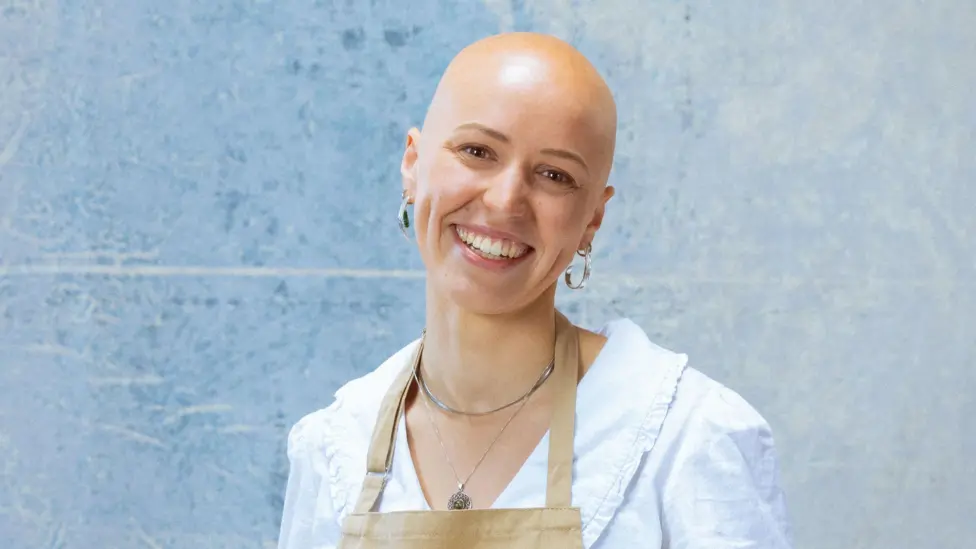 Jasmine in a white shirt and beige apron on a blue background