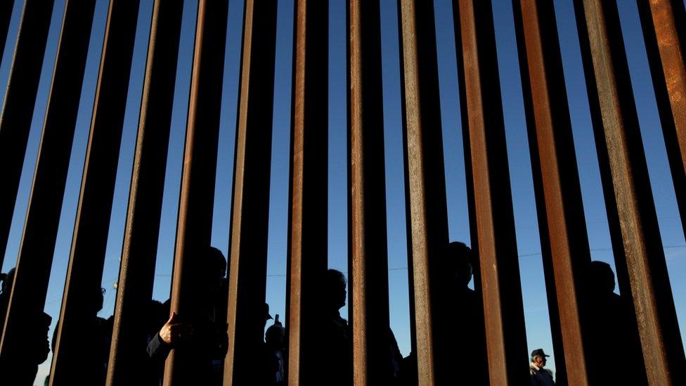 People stand at wall at the southern border