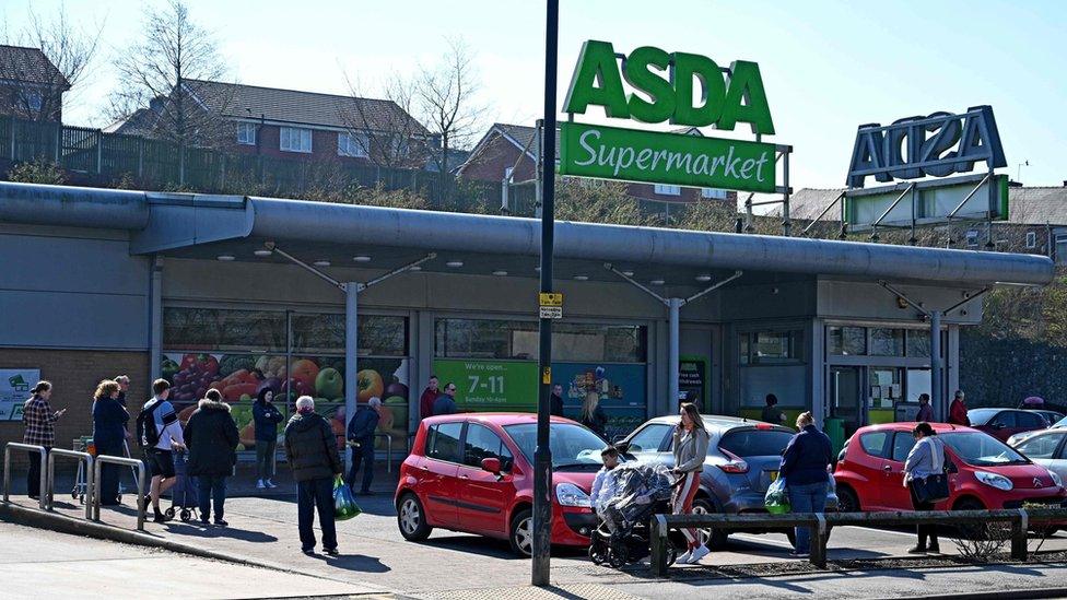 Shoppers queue outside a supermarket