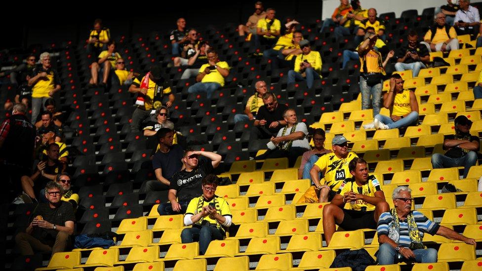 Fans at Borussia Dortmund watch from socially distanced positions