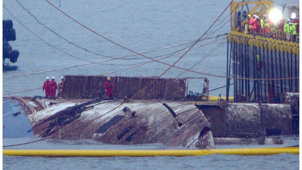 Salvage team workers stand on the hull of the Sewol ferry in waters near Jindo island, South Korea, 23 March 2017.