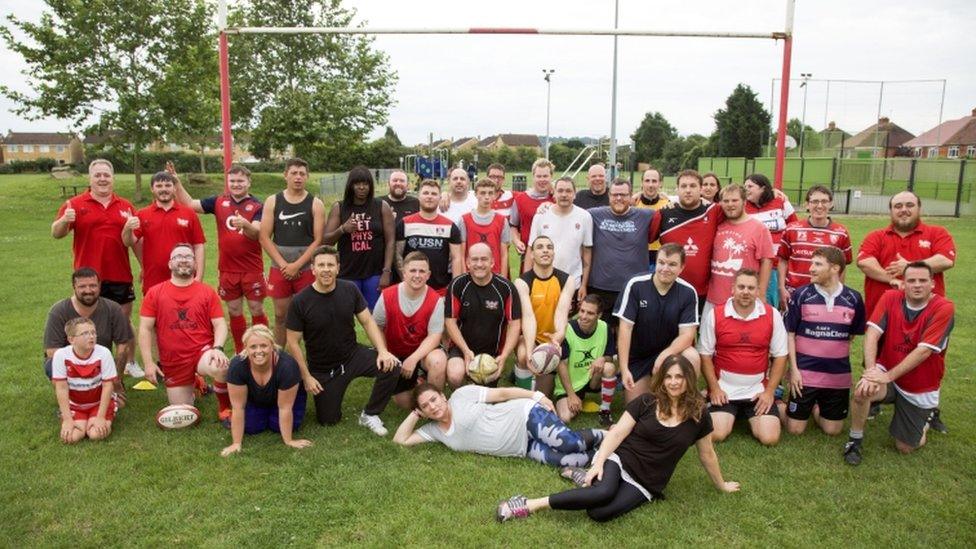 Group in sports kit on a rugby pitch, smiling