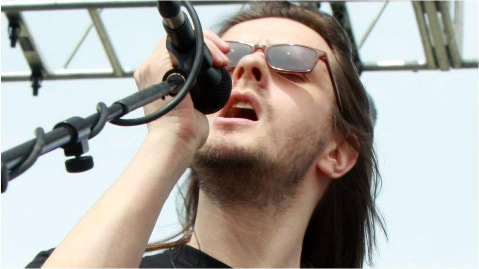 Progressive rock singer performing with microphone in concert setting
