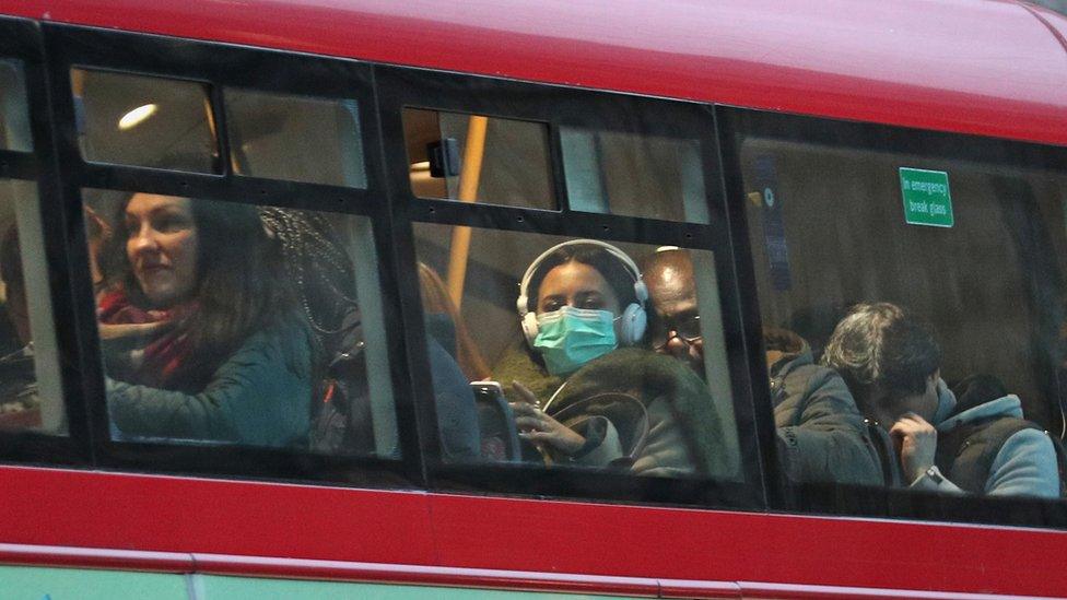 A woman wearing a face mask on a bus in London