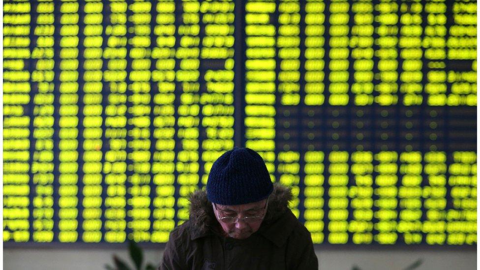 A stock investor pauses near a display board showing stock prices in green to symbolize a fall in price, at a brokerage house in Jiujiang on Monday