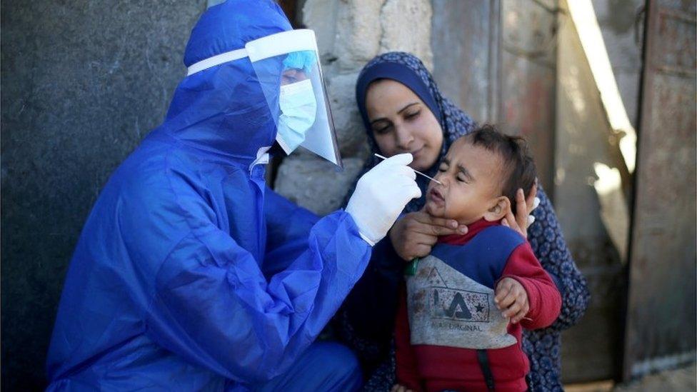 A Palestinian medical worker collects a swab sample from a boy to be tested for the coronavirus disease (COVID-19), in the southern Gaza Strip