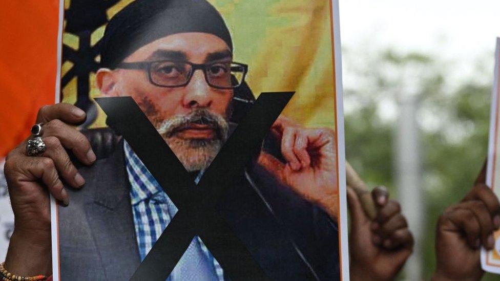 Man holding sign depicting Gurpatwant Singh Pannun