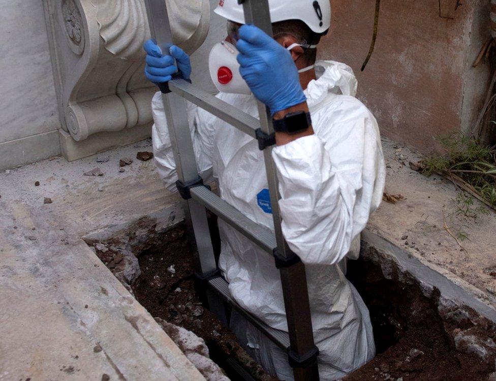 A man is seen on a ladder as people open a tomb in a cemetery on the Vatican's grounds to test the DNA of bones to help solve the 36-year-old disappearance of a teenage daughter of a clerk in the Holy See, in the Vatican, 11 July 2019