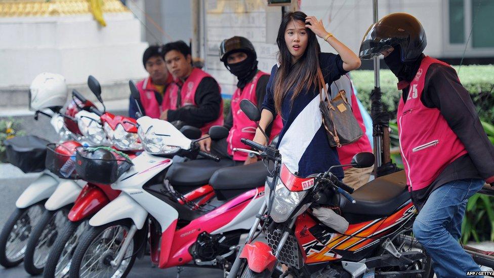 A Thai office worker (2nd R) negotiating for a motorbike taxi ride for transport in Bangkok