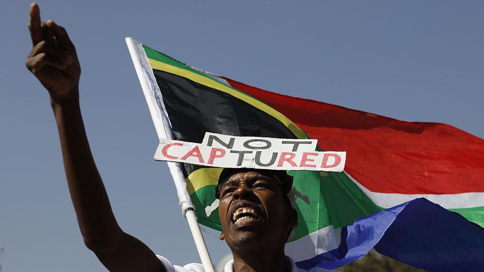 A supporter of the Organisation Undoing Tax Abuse (Outa) holds a South African flag while picketing outside Raymond Zondos judicial commission of inquiry into state capture at Parktown on August 20, 2018 in Johannesburg, South Africa.