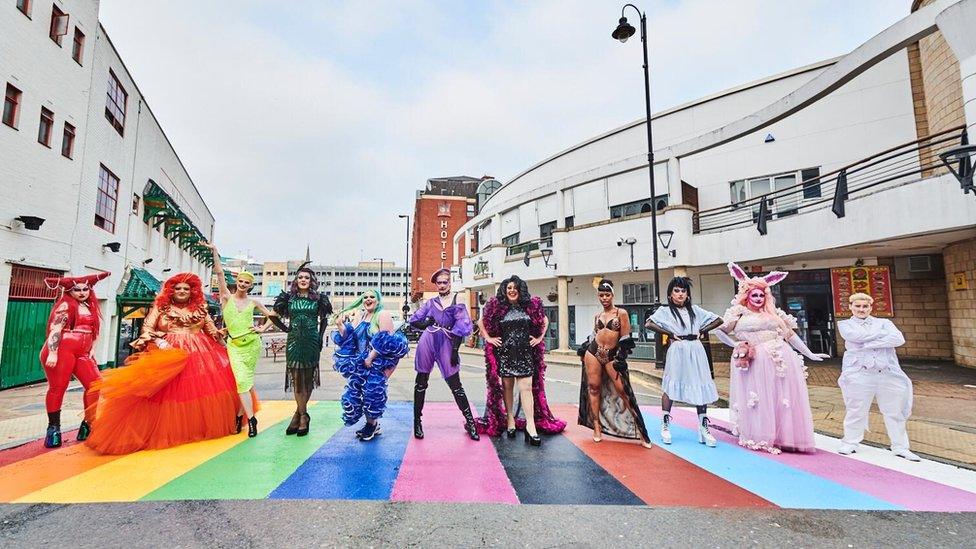 Drag artists standing on rainbow crossing